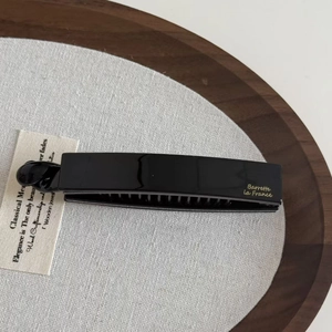 Détail de la pince banane française noire brillante avec lettrage doré chic