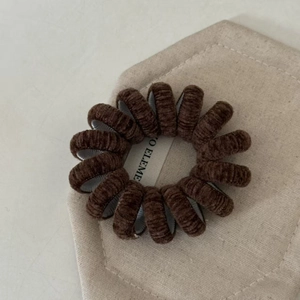 Gros plan détaillé sur l'élastique à cheveux spirale en velours côtelé marron foncé