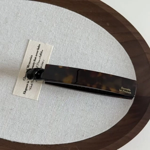 Gros plan d'une barrette à cheveux en écaille avec lettrage français doré sur plateau