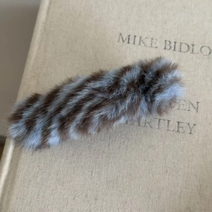 Gros plan d'une pince à cheveux rayée en peluche marron et bleue sur un livre ancien
