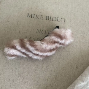 Vue détaillée de la pince à cheveux en peluche rayée marron et crème sur tissu neutre