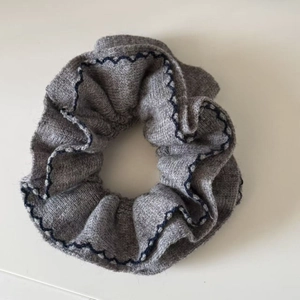 Détail du chouchou en maille grise avec coutures ondulées bleues et texture de tricot