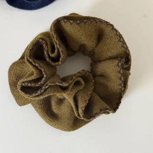 Détail de la texture tricotée et bordure violette contrastée sur chouchou vert olive foncé