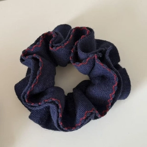 Détail du chouchou en maille bleu marine avec bords surjetés rouges et texture côtelée