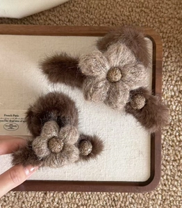 Detailed macro view of plush flower hair clips in autumn brown faux fur texture