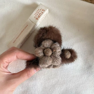 Detailed view of dark brown plush hair claw clip with a knitted beige flower decoration