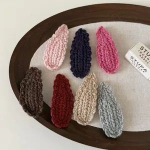 Macro view of handmade crochet wave hair clips in seven colors on a wooden tray