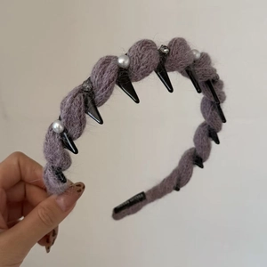 Dettaglio della fascia lavorata a maglia viola con borchie nere e perle