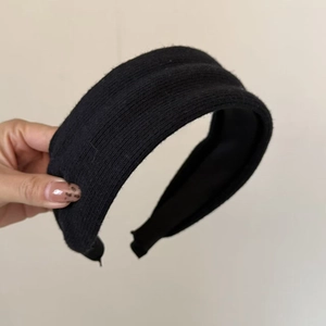 Detailed close-up of a wide black knitted headband featuring a thick ribbed texture fabric