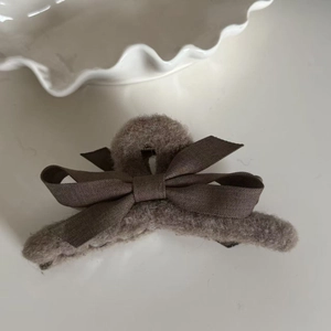 Close-up of taupe plush hair claw clip featuring a soft faux fur texture and ribbon bow