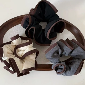 Brown edged fabric scrunchies set in black, cream and grey on a wooden tray