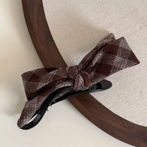 Close-up of vintage brown plaid bow hair clip on a natural linen background