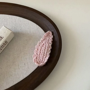 Close-up of pink handcrafted knit wool drop hair clip with soft wavy woven texture