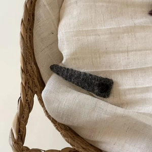 Detalle de pinza para el pelo con corazón de terciopelo gris oscuro en lino beige