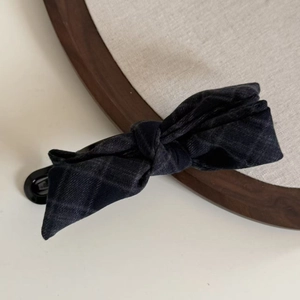 Detail of grey plaid bow banana hair clip with a focus on the textured fabric material