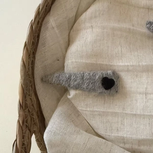 Detalle de horquilla de punto gris con aplique de corazón negro sobre textura tejida
