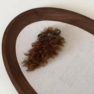 Close-up of soft brown faux fur hair clip featuring a delicate leather bow detail