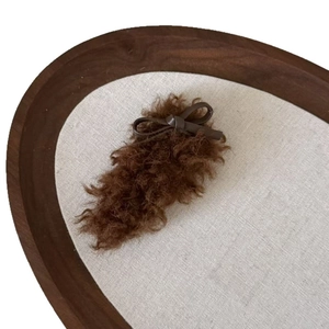 Plush faux shearling bow hair clip in brown on a vintage tray for winter styling