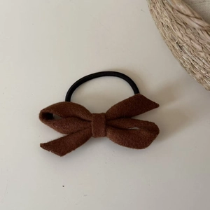 Close-up of brown wool bow hair tie with durable black elastic rope on white surface