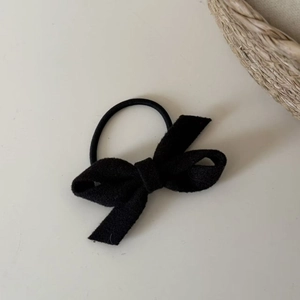 Detail view of a black velvet bow hair tie with a durable elastic band on soft background