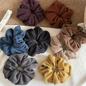 Detail view of eight multi-colored knitted scrunchies with soft woven texture