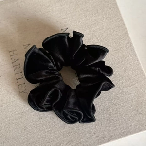 Macro detail of the elegant black velvet scrunchie showing fabric texture and soft luster