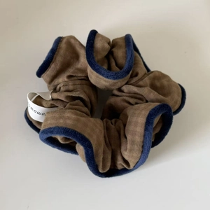Detaillierte Textur des blau-braunen Patchwork-Scrunchies mit weichem Samtbesatz