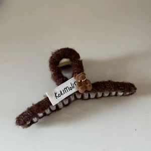 Detail of plush dark brown bear hair claw clip with pearls and white brand label