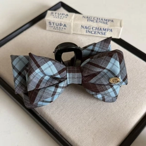 Navy blue plaid bow hair claw clip with vintage gold love metal tag on linen tray