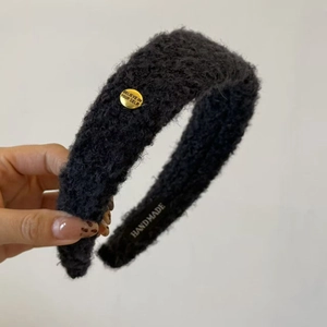 Détail du serre-tête en peluche noire avec emblème métallique doré Believe In Yourself