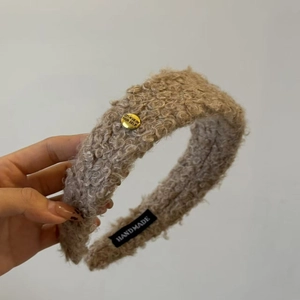 Détail d'un serre-tête en laine de mouton kaki avec bouton doré et étiquette tissée