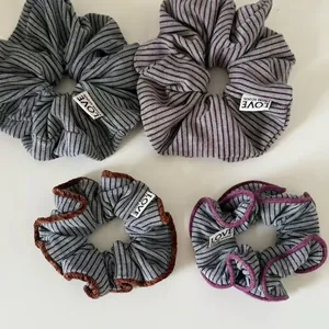Set of four grey and purple striped knit scrunchies with soft velvet edges and labels