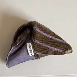 Macro shot of triangle knitted hair clip with handmade label in brown and purple stripes