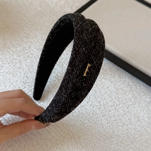 Detail of tweed headband with black and white texture and golden handmade metal logo