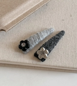 Detail of triangle knit hair clips with rhinestones and flower charms in grey and black