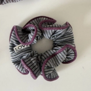 Detailed shot of striped gray knit hair scrunchie with velvet trim and LOVE label