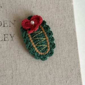 Close-up of handmade crochet Christmas tree hair clip with red bow and pearl detail