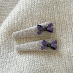 Cream white hair clip with purple bow and wool texture on soft knit background