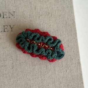 Detail of handmade crochet hair clip with vintage red base and green scalloped edge