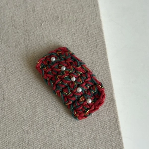 Close-up of handmade crochet Christmas hairpin with red green yarn and white pearls