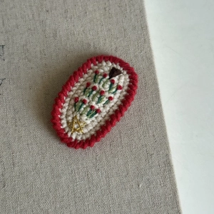Close-up of handmade crochet Christmas hair clip with green tree and red wave edges