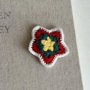 Close-up of handmade crochet Christmas star clip with red green yellow and white yarn