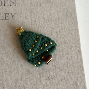 Macro detail of handmade crochet Christmas tree hair clip with golden bead accents