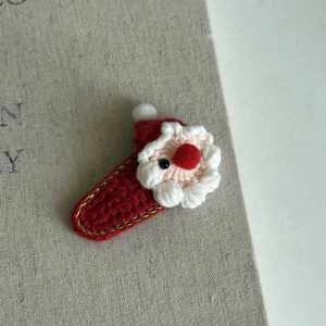 Close-up of handmade crochet Santa Claus hair clip with festive red and white wool texture