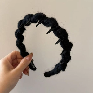 Punk style black knitted hairband with metallic cone spikes and a textured yarn finish