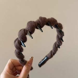 Close-up of dark brown knitted headband with anti-slip teeth and handmade label