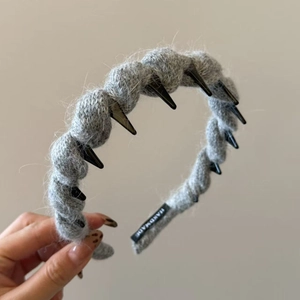 Detail of gray knitted headband showing the handmade label and black spiked rivet design