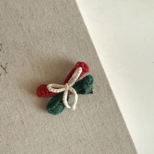 Detail of handmade crochet Christmas bow hair clip with red and green yarn texture
