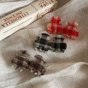 Three pairs of small plaid hair claws in red black and brown on a linen background