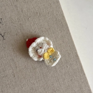 Handmade crochet Santa Claus hair clip with red hat and white beard on rustic fabric